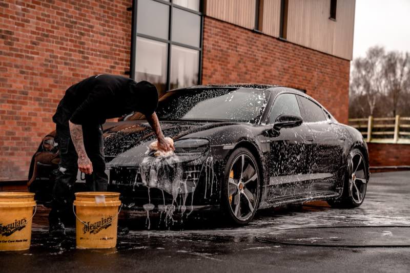 A detailer hand-washing a car with thick foam